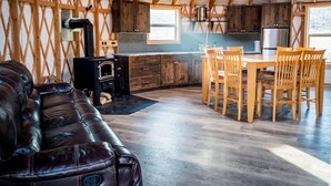 Un intérieur chaleureux avec un canapé en cuir, une table à manger en bois et un poêle à bois.