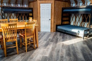 A cozy room with a wooden dining table, chairs, a bench, and a door. - Secluded Modern Yurt with Sauna Perfect for Small Groups in Boise, Idaho (Boise)