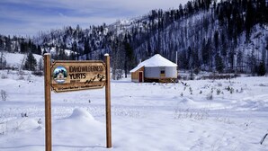 Une pancarte en bois indiquant « Idaho Wilderness Yurts », avec une yourte en arrière-plan.
