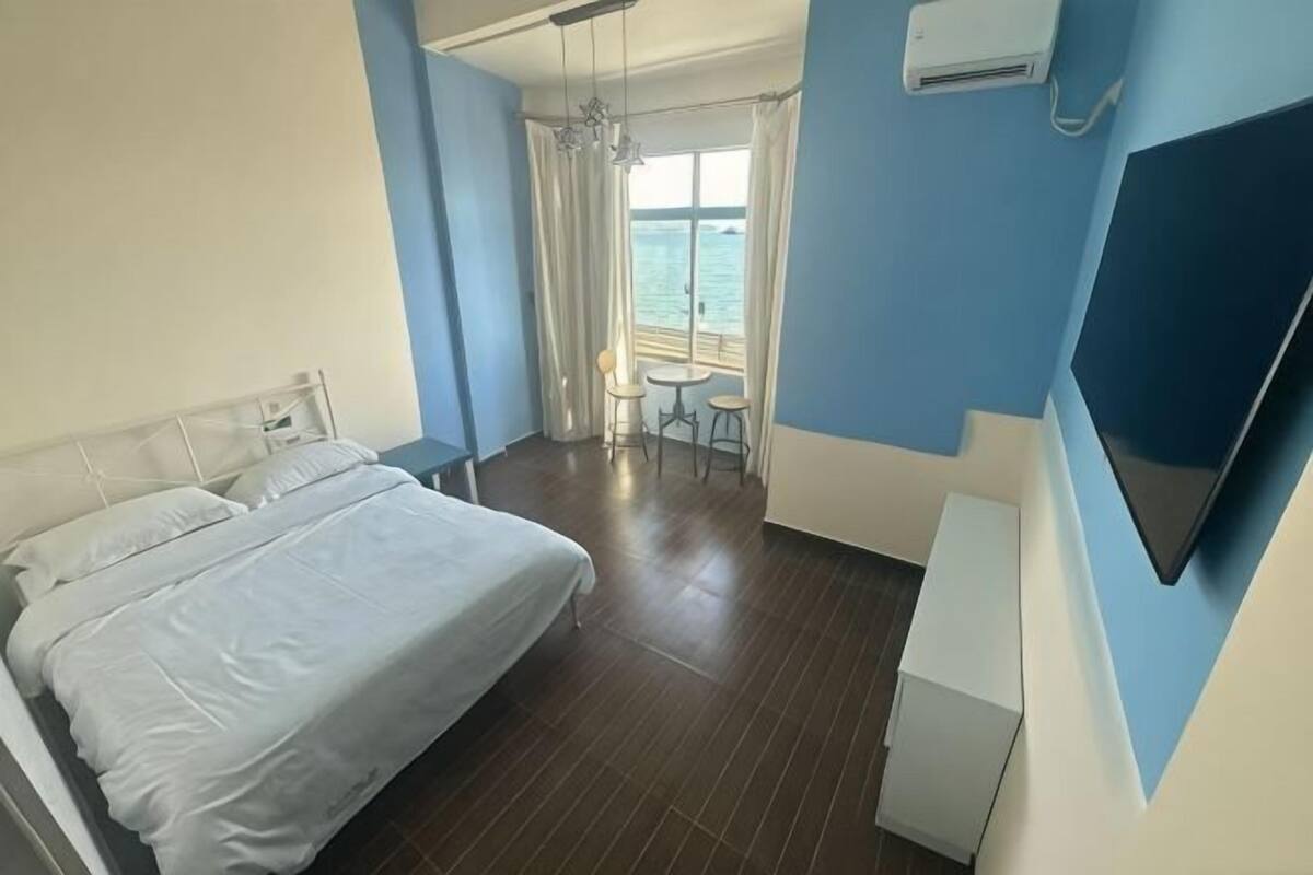 Hotellihuone, jossa on sänky, työpöytä, tuoli, televisio ja ikkuna, jossa on verhot.