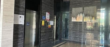 Un ascensor moderno con puertas de vidrio, piso pulido y un panel decorativo en la pared.