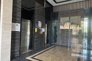 Un ascensor moderno con puertas de vidrio, piso pulido y un panel decorativo en la pared.