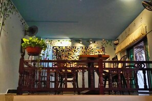 Una habitación con un separador de madera, una planta en maceta y una mesa con sillas.