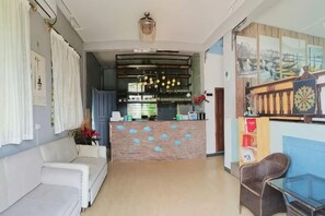 Un vestíbulo de hotel con mostrador de recepción, un sofá y una zona de bar.
