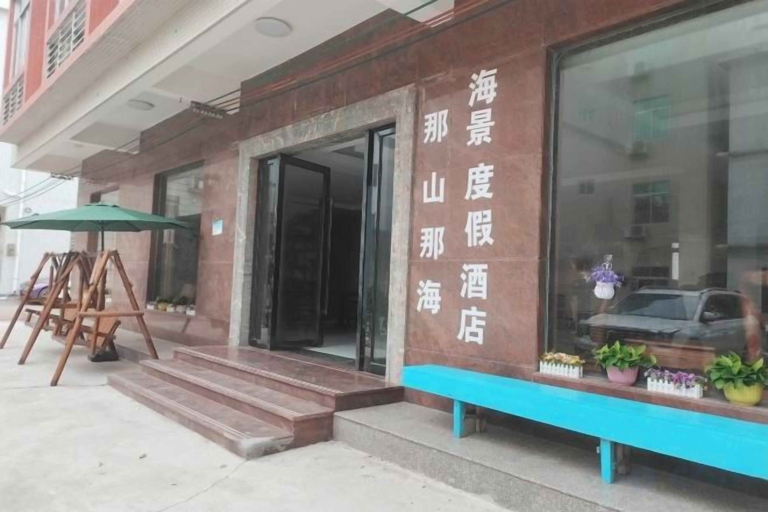 A hotel entrance with a visible name sign, steps leading to the door, and a bench outside.