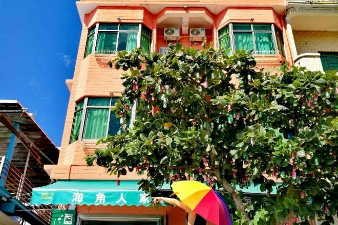 Un edificio con toldo verde y un árbol en primer plano.