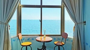 Una habitación con un ventanal grande, dos sillas y una pequeña mesa.