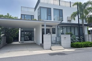 Uma casa moderna de dois andares, com entrada coberta, grandes janelas e varanda.