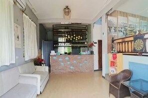 Un vestíbul d'hotel amb una recepció, un sofà i una zona de menjador.