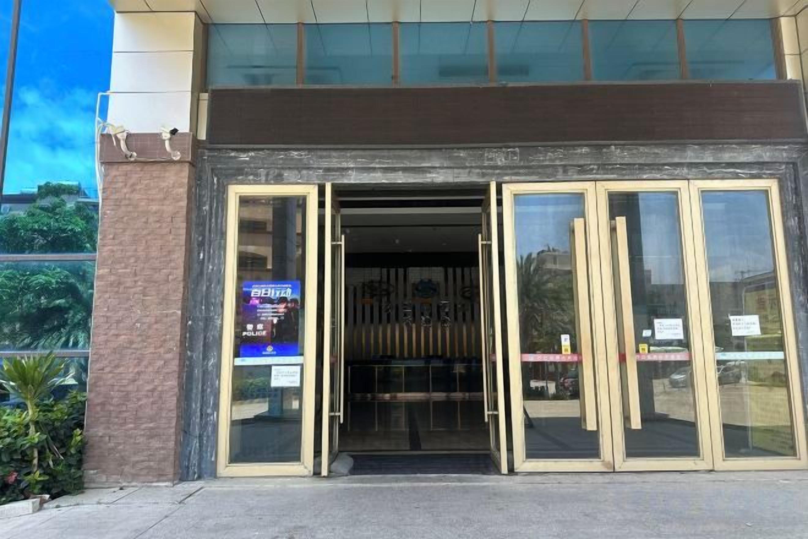 Una entrada de edificio con puertas de vidrio y un letrero a la izquierda.
