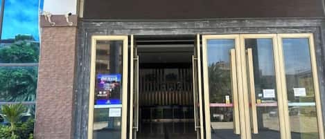 Una entrada de edificio con puertas de vidrio y un letrero a la izquierda.
