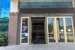 A building entrance with glass doors and a sign on the left.