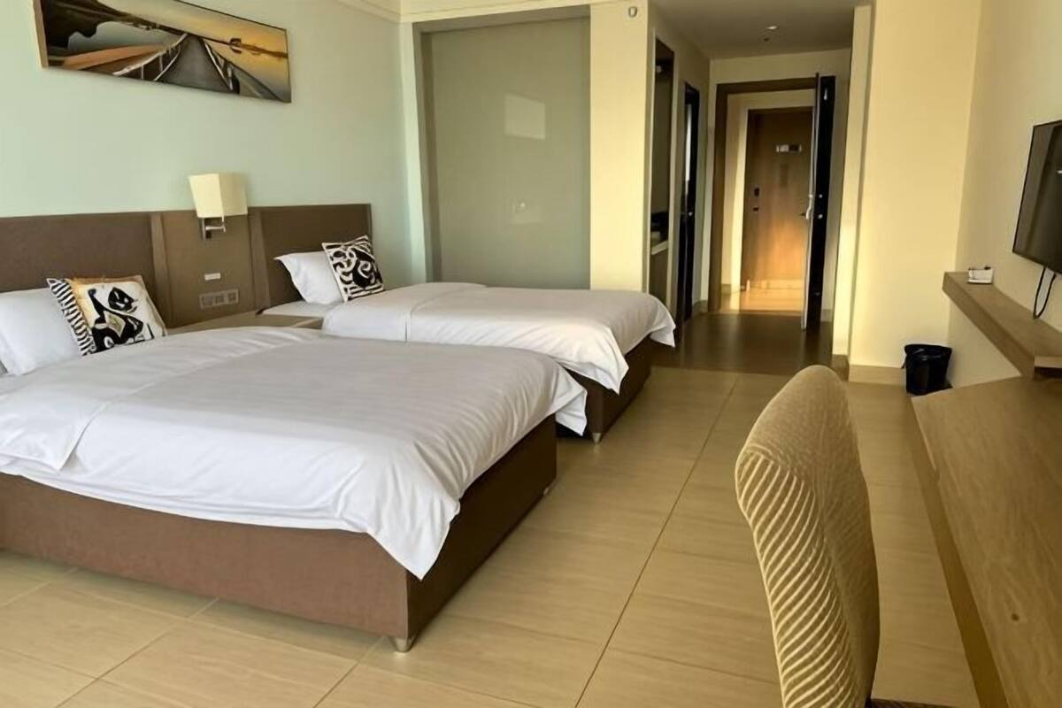 Hotellihuone, jossa on kaksi sänkyä, televisio, työpöytä ja tuoli.