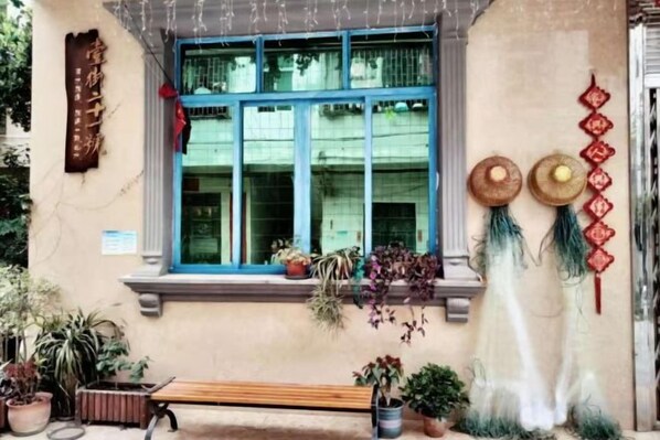 A building facade with a window, potted plants, a bench, and decorative items.