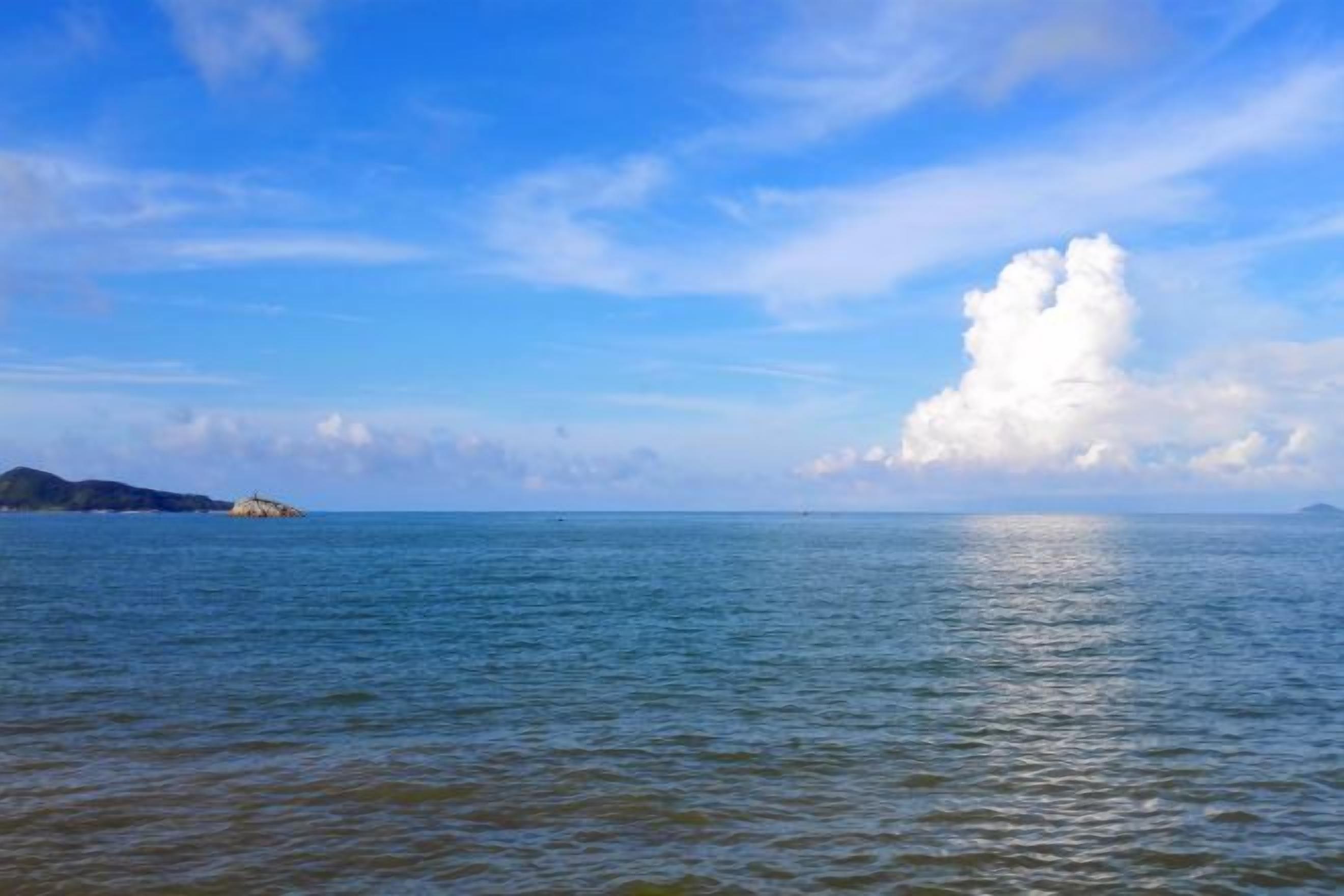 Mar tranquila con cielo despejado y una masa terrestre a lo lejos.