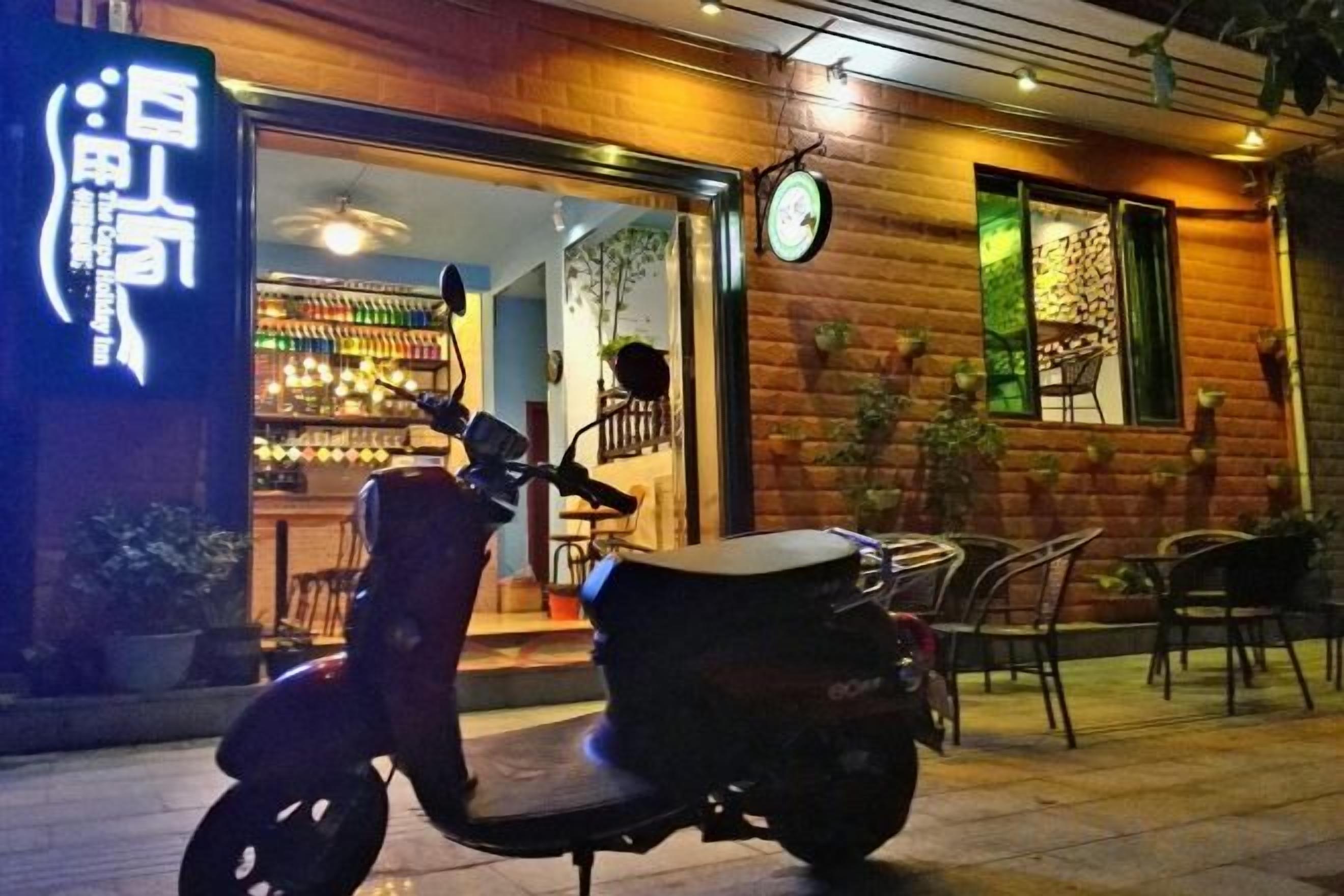 A scooter parked outside a building with a visible entrance and a clock on the wall.