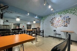 Un interior de restaurante con mesas, sillas, lámparas colgantes y una pared decorada con fotografías.
