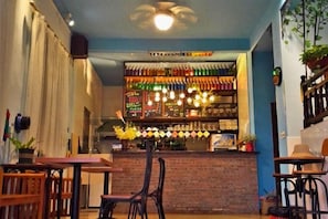 Zona de bar con mostrador de ladrillo, luces colgantes y una variedad de botellas.