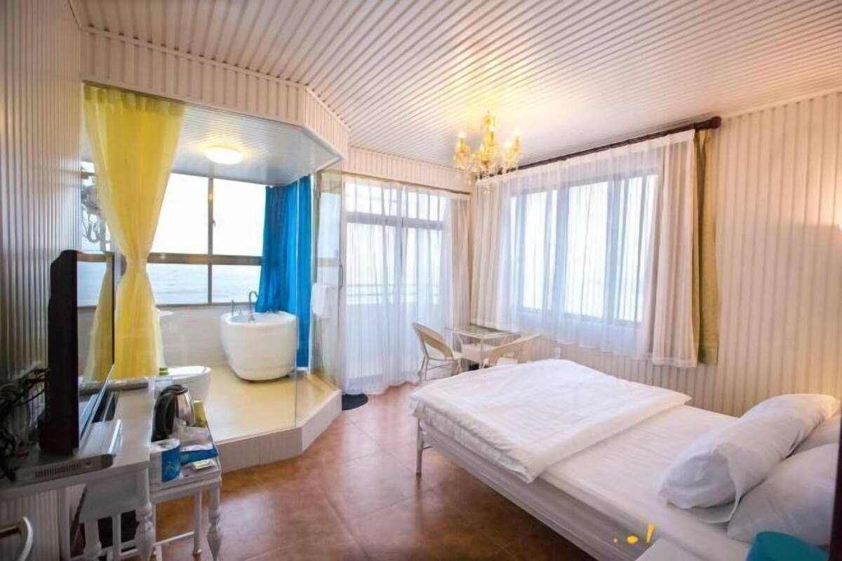 Hotellihuone, jossa on sänky, työpöytä, tuoli, kylpyamme ja peili.