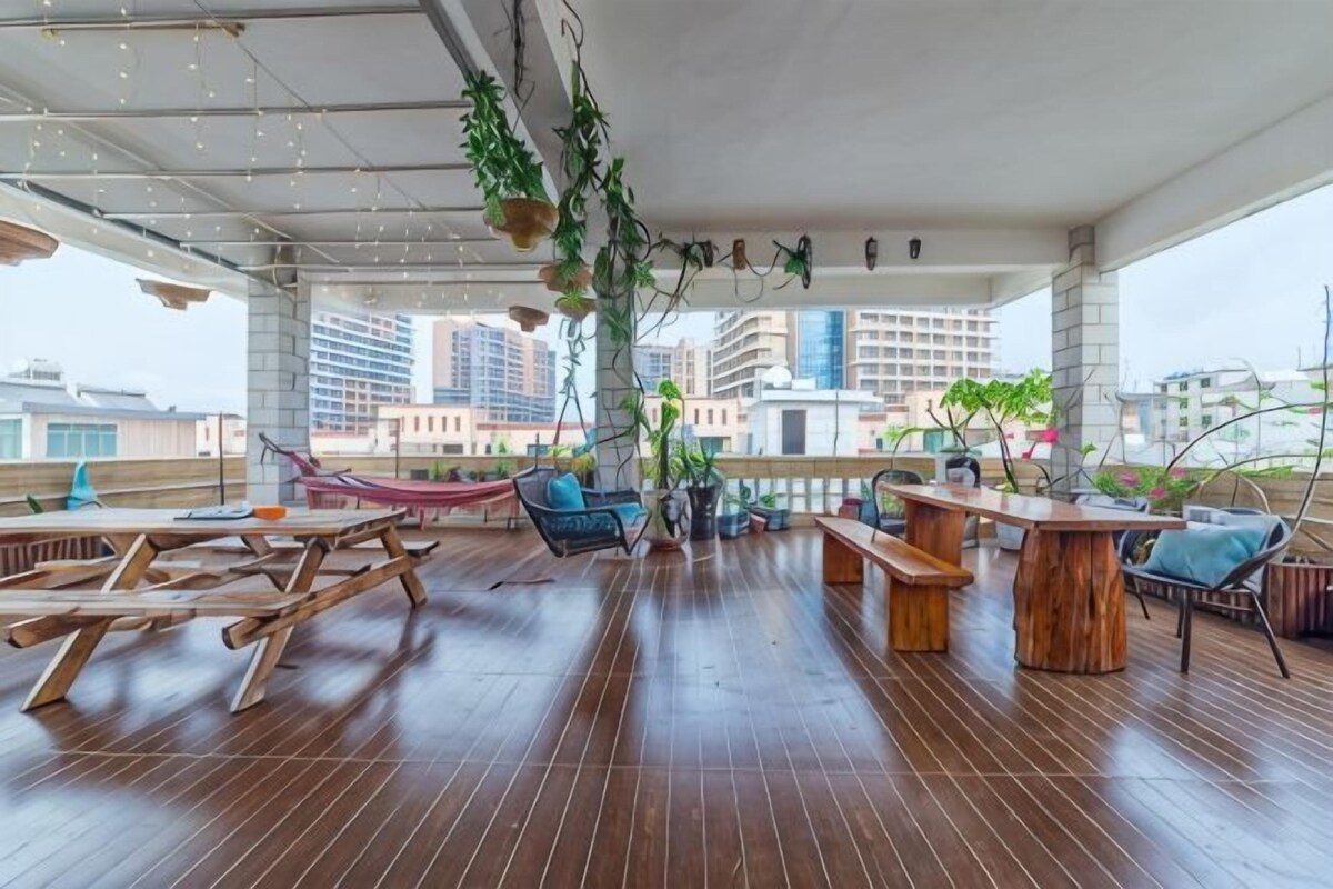 Un salón de planta abierta con piso de madera, arreglos de asientos y plantas colgantes.