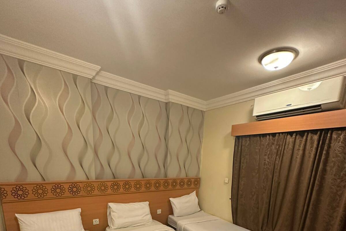Ein Hotelzimmer mit zwei Einzelbetten, einem Deckenventilator und einer Wandklimaanlage.