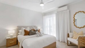 Ein Schlafzimmer mit Bett, Nachttisch, Lampe und einem Sessel.