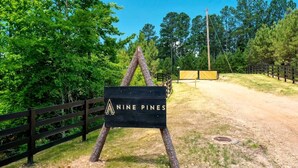 En skylt med texten ”Nine Pines”, med ett trästaket och träd i bakgrunden.