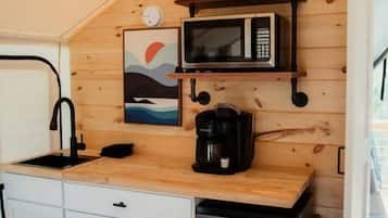 A compact kitchenette with a microwave, coffee maker, and a small sink.