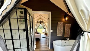 A bedroom with a large window, a bed, and a view of the outdoors.