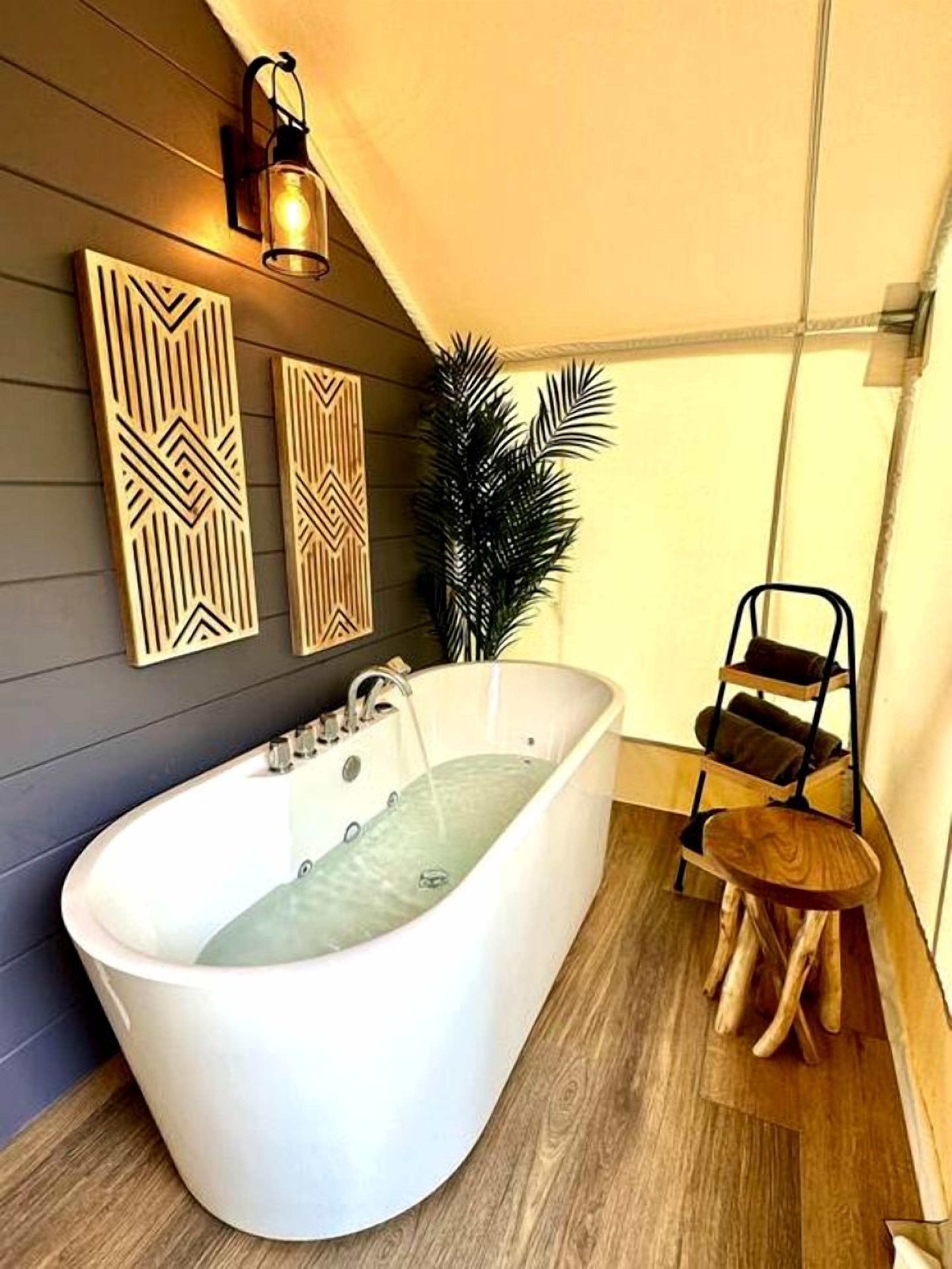 A modern bathroom with a freestanding bathtub, wooden wall decor, and a potted plant.