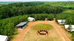 Un camping con varias cabañas, un espacio común con sillas y un sendero de tierra que las conecta.