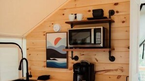 Ett litet, praktiskt pentry med mikrovågsugn, kaffebryggare och ett litet handfat.