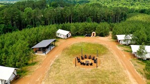 A campsite with several cabins, a central gathering area with chairs, and a dirt path connecting them.