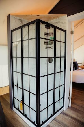Una habitación con un separador de vidrio, una cama y suelo de madera.
