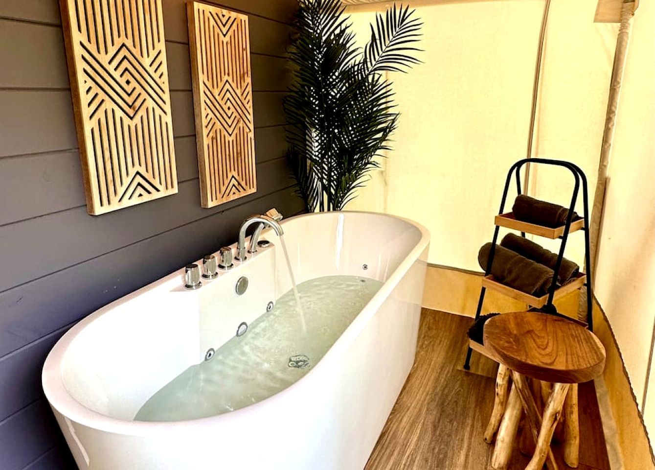 A modern bathroom with a freestanding bathtub, wooden wall decor, and a plant.