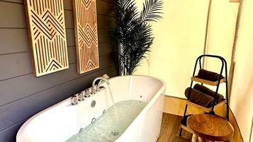 A modern bathroom with a freestanding bathtub, wooden wall decor, and a plant.