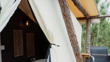 Una tenda con una vasca da bagno, una sedia e un pontile di legno.