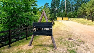 Segnaletica per 'Nine Pines', con una recinzione in legno e alberi sullo sfondo.