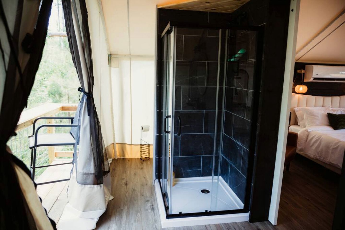A room with a shower, a bed, and a balcony.