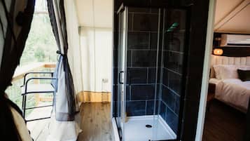 A room with a shower, a bed, and a balcony.