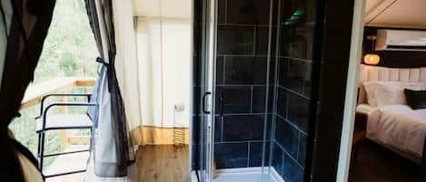 A room with a shower, a bed, and a balcony.