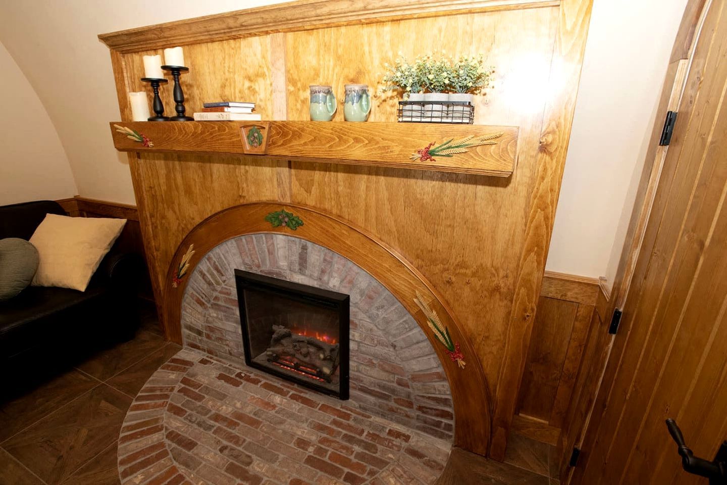 A fireplace with a brick surround, a wooden mantel above it, and a shelf with decorative items.