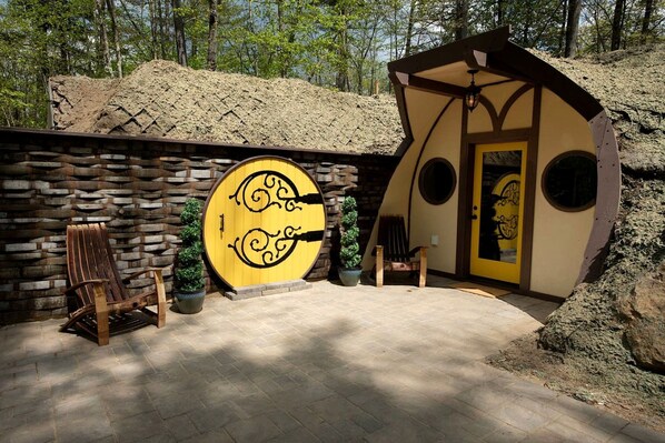 A rustic building with a stone wall, a wooden door with circular windows, and a bench.