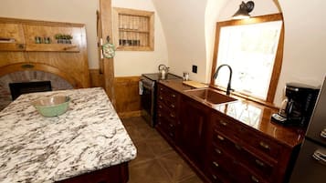 A kitchen with a marble countertop, wooden cabinetry, a built-in oven, and a window with natural light.