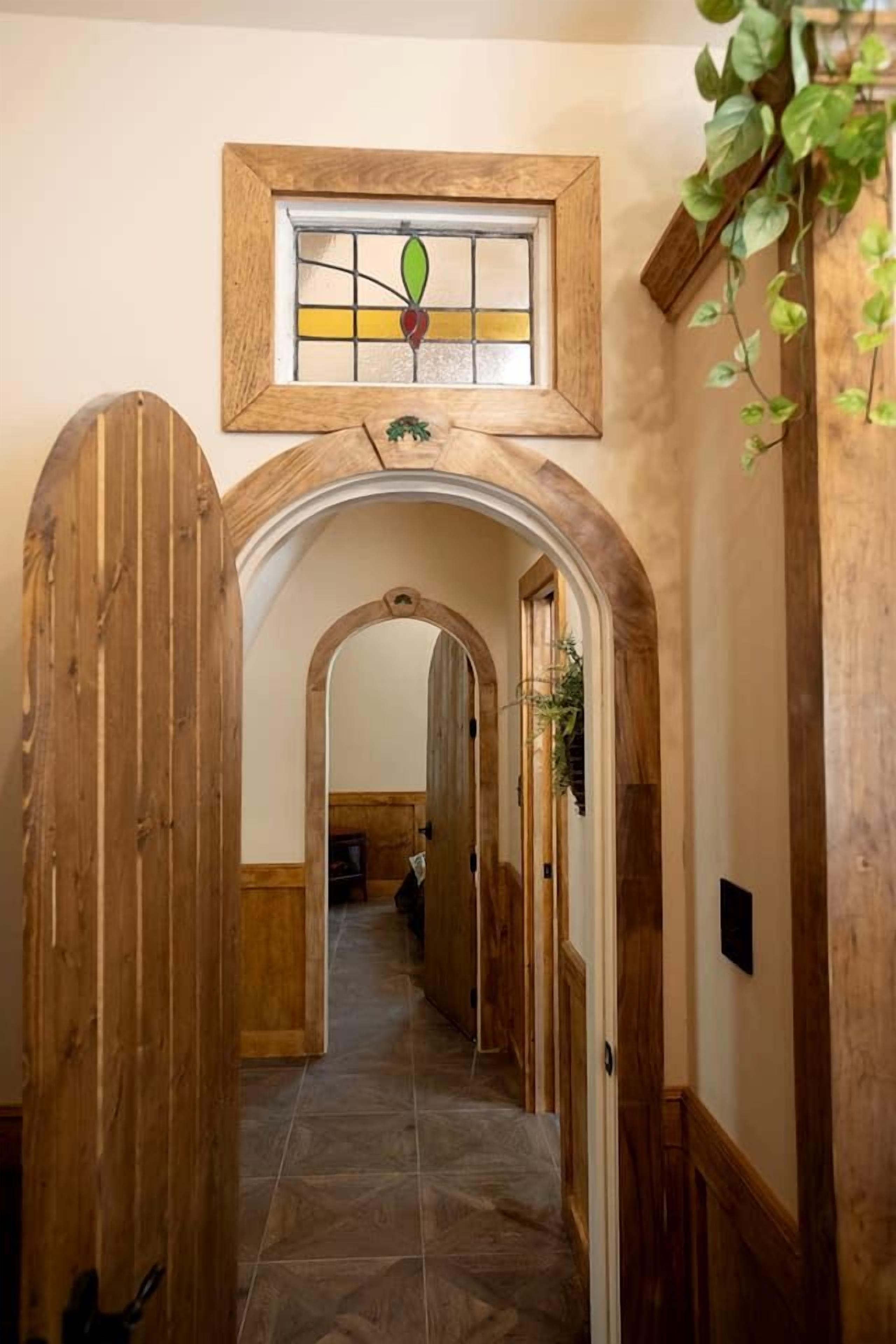 Un couloir avec des portes en bois, un vitrail et un sol carrelé.