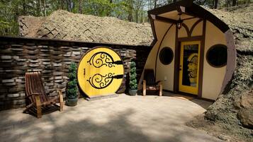 A rustic building with a stone wall, a wooden door with circular windows, and a bench.