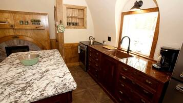 A kitchen with a marble countertop, wooden cabinetry, a built-in oven, and a window with natural light.