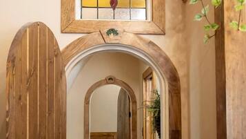 A hallway with wooden doors, a stained glass window, and a tiled floor.