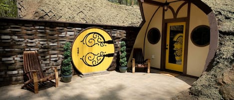 A rustic building with a stone wall, a wooden door with circular windows, and a bench.