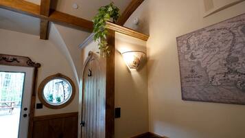 A room with a wooden door, a round window, a wall-mounted map, and a hanging plant.